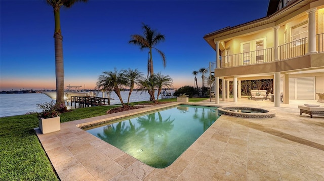 view of swimming pool featuring stairway, a patio, a pool with connected hot tub, and a water view