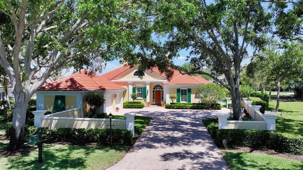 228 Saint James Park, Osprey, FL 34229 - mediterranean / spanish house featuring a tile roof, decorative driveway, a front lawn, and fence private yard