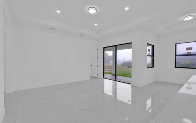 unfurnished room featuring a raised ceiling, recessed lighting, and marble finish floor