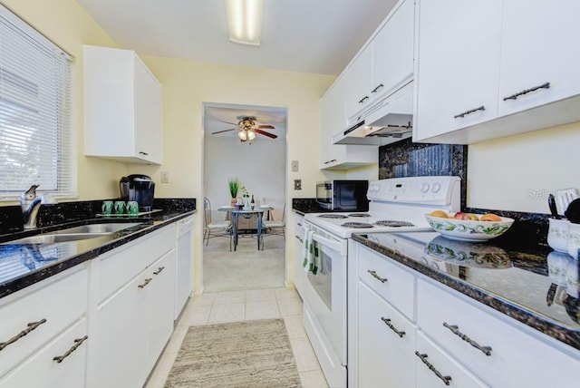 kitchen with white appliances, a sink, under cabinet range hood, ceiling fan, and dark stone countertops