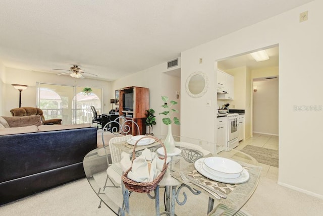 dining space featuring a ceiling fan, light carpet, and baseboards