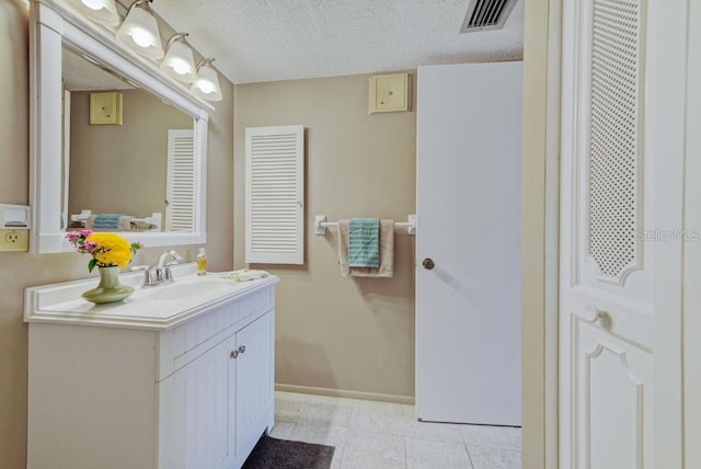 bathroom with vanity, a textured ceiling, baseboards, and tile patterned floors