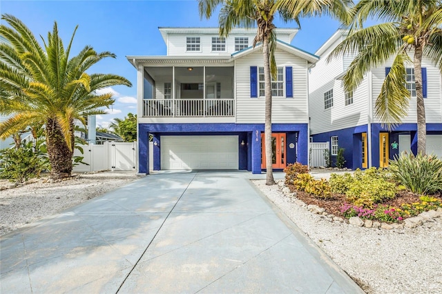 coastal home with a gate, concrete driveway, an attached garage, fence, and stucco siding