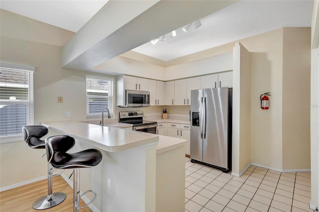 6415 39th Ave W, Bradenton, FL 34209 - kitchen with a peninsula, a breakfast bar, light countertops, a sink, and stainless steel appliances