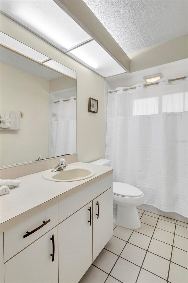 6415 39th Ave W, Bradenton, FL 34209 - full bathroom featuring tile patterned flooring, vanity, toilet, a textured ceiling, and a shower with curtain