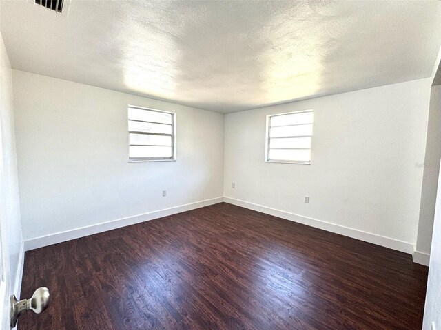 9430 Glen Moor Ln, Port Richey, FL 34668 - spare room with dark wood-style floors, baseboards, plenty of natural light, and a textured ceiling