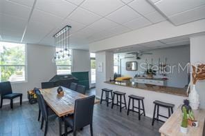 dining space with a drop ceiling and wood finished floors