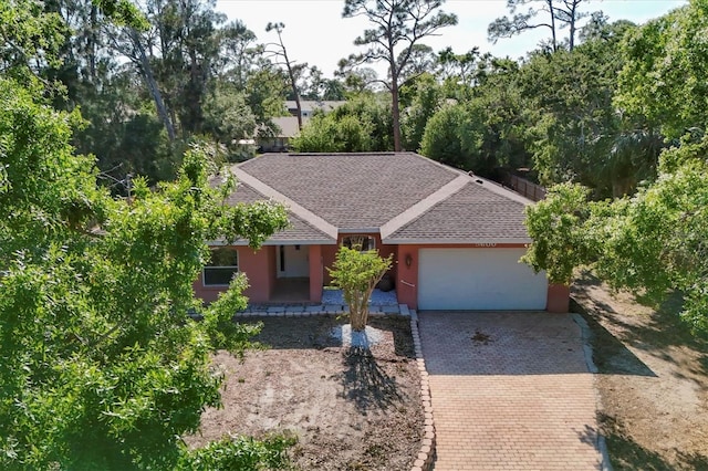 single story home with decorative driveway, a shingled roof, an attached garage, and stucco siding