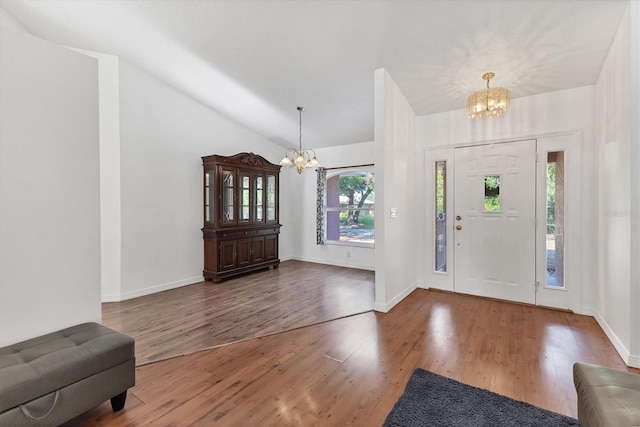 entryway with a notable chandelier, vaulted ceiling, wood finished floors, and baseboards