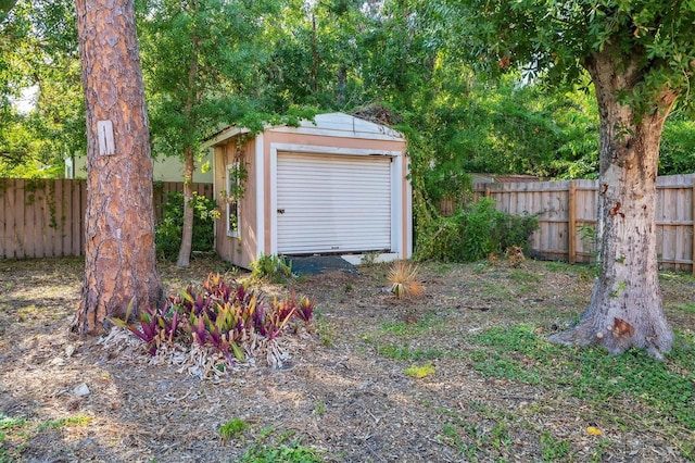 garage featuring fence and a shed