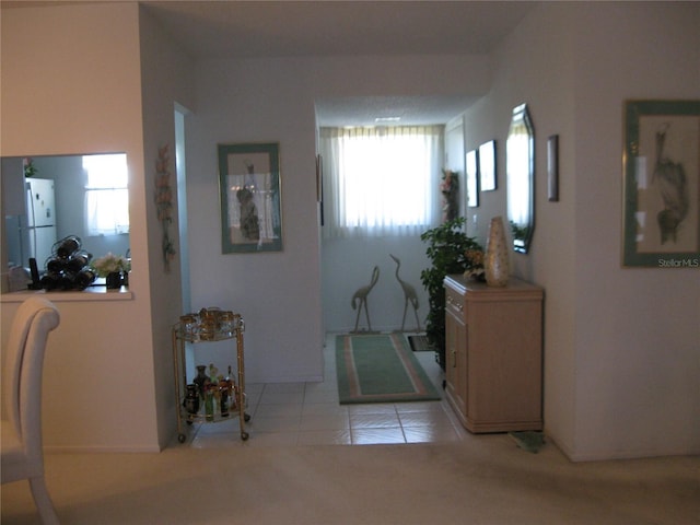 corridor with light colored carpet, light tile patterned floors, and a wealth of natural light
