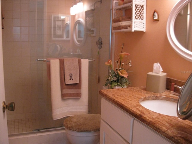 full bathroom with toilet, tiled shower, and vanity