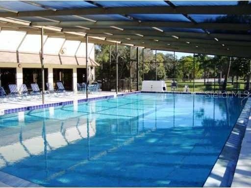 community pool with a patio area and glass enclosure