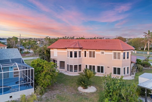 4405 Harbor Blvd, Port Charlotte, FL 33952 - back of property featuring a tiled roof, stucco siding, glass enclosure, and a lawn
