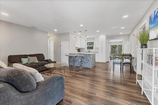 living area with dark wood-type flooring, visible vents, and recessed lighting