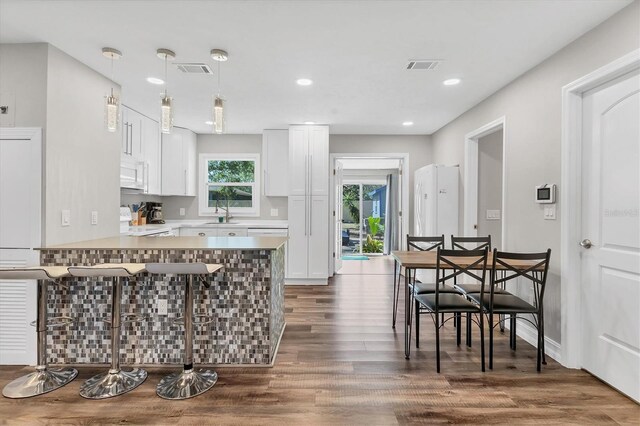 kitchen featuring visible vents, a breakfast bar area, a peninsula, range, and white cabinetry