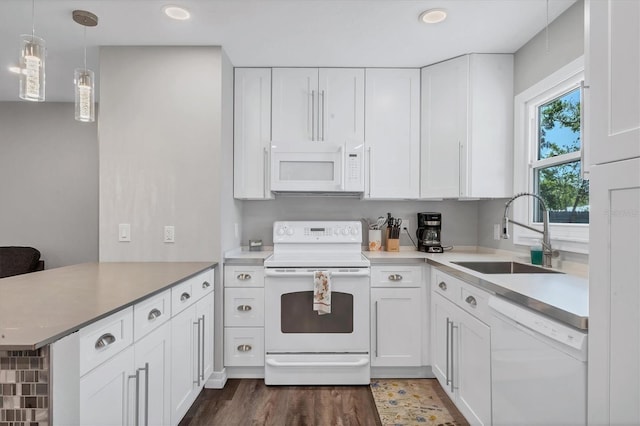 kitchen featuring white cabinets, a peninsula, white appliances, and a sink