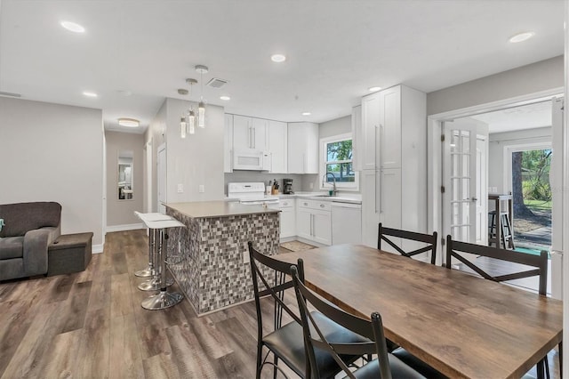 dining area with baseboards, wood finished floors, visible vents, and recessed lighting
