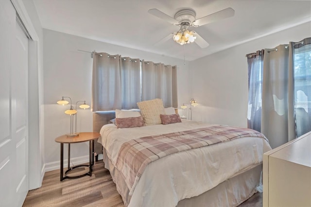 bedroom featuring ceiling fan, baseboards, a closet, and light wood-style flooring