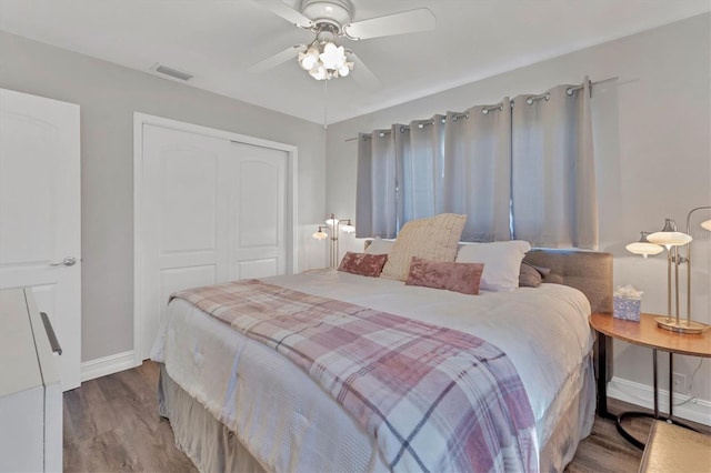 bedroom featuring baseboards, wood finished floors, visible vents, and a closet