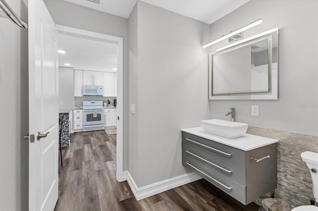 bathroom featuring wood finished floors, toilet, and vanity