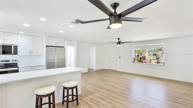 6628 Keystone Dr, Sarasota, FL 34231 - kitchen featuring appliances with stainless steel finishes, a ceiling fan, light countertops, a kitchen bar, and recessed lighting
