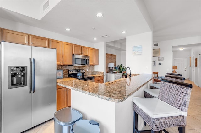 7803 Grand Estuary Trl Unit 102, Bradenton, FL 34212 - kitchen featuring a breakfast bar, light tile patterned floors, light stone countertops, visible vents, and stainless steel appliances