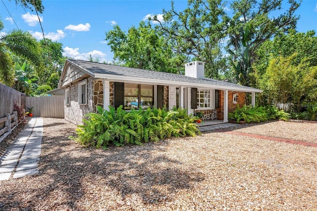 ranch-style home with stone siding, a chimney, and fence