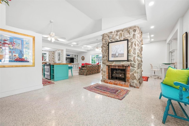 living area featuring recessed lighting, a stone fireplace, baseboards, and ceiling fan