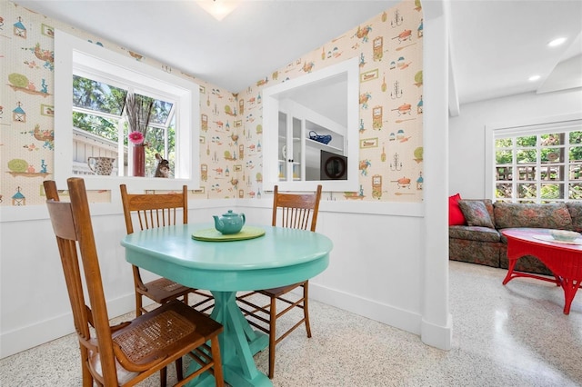 dining space with a wainscoted wall, baseboards, recessed lighting, speckled floor, and wallpapered walls