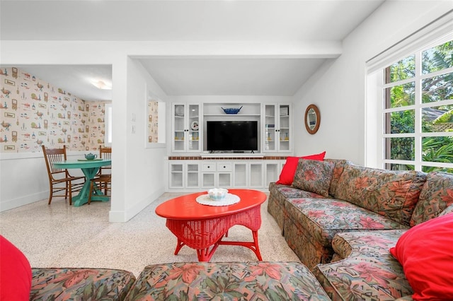 living room featuring beamed ceiling, baseboards, and speckled floor