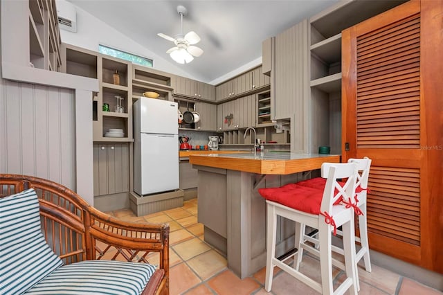 kitchen with lofted ceiling, wooden counters, open shelves, freestanding refrigerator, and ceiling fan