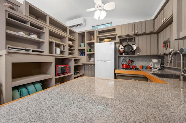 kitchen with open shelves, a wall unit AC, gray cabinets, a sink, and freestanding refrigerator