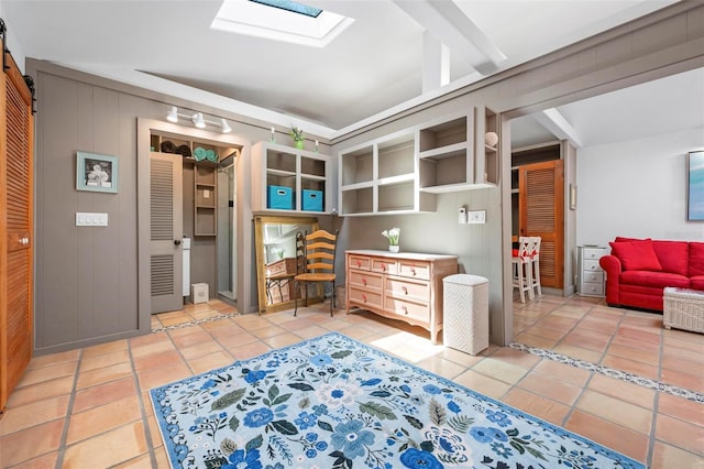 interior space featuring light tile patterned flooring, a skylight, and wood walls