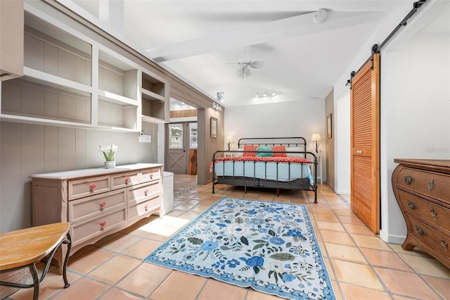 bedroom featuring vaulted ceiling with beams, light tile patterned floors, and a barn door