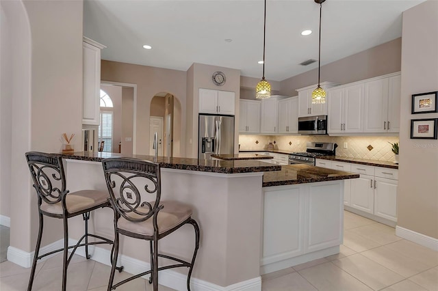 3738 Eagle Hammock Dr, Sarasota, FL 34240 - kitchen featuring hanging light fixtures, white cabinetry, a kitchen bar, backsplash, and appliances with stainless steel finishes