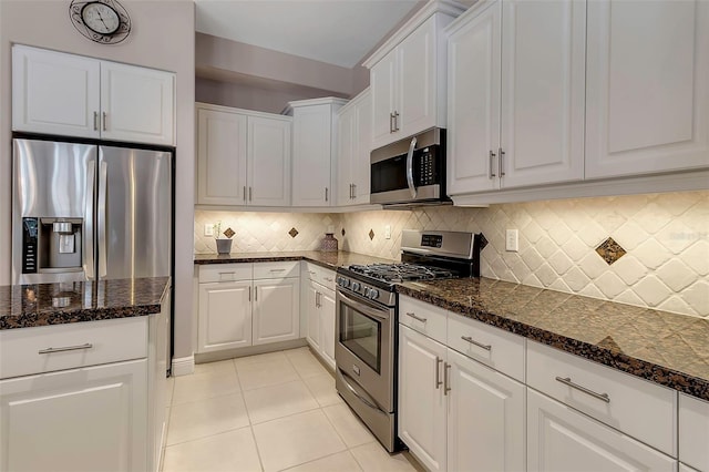 3738 Eagle Hammock Dr, Sarasota, FL 34240 - kitchen with dark stone countertops, light tile patterned floors, stainless steel appliances, white cabinets, and backsplash