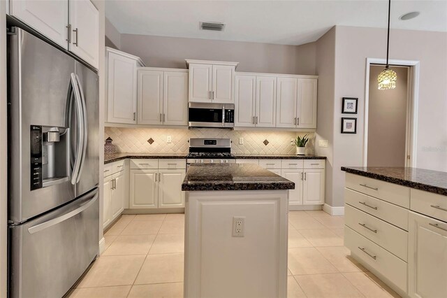 3738 Eagle Hammock Dr, Sarasota, FL 34240 - kitchen with decorative backsplash, light tile patterned floors, appliances with stainless steel finishes, visible vents, and a kitchen island