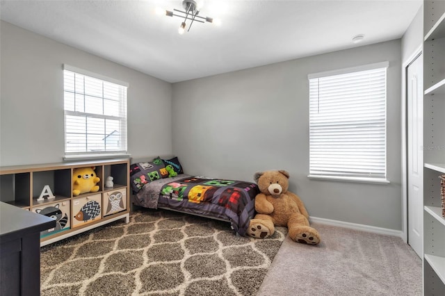 carpeted bedroom featuring baseboards and a closet