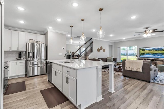 kitchen with stainless steel appliances, open floor plan, and ornamental molding