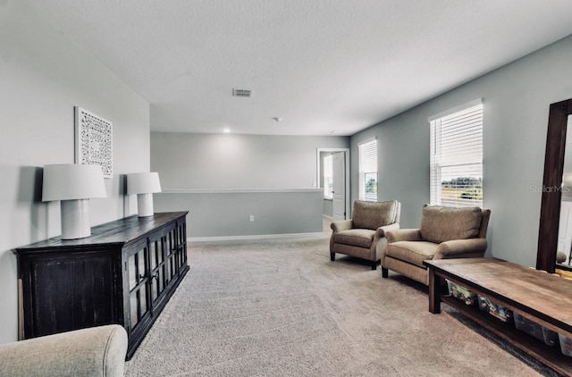 living area featuring baseboards, visible vents, and carpet