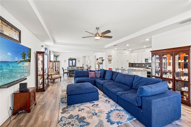 7322 34th Ct E, Sarasota, FL 34243 - living room with light wood-style flooring, ceiling fan, a tray ceiling, and recessed lighting