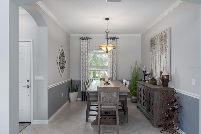dining room with light tile patterned floors, arched walkways, crown molding, and baseboards