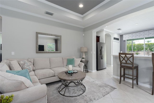 living room featuring arched walkways, light tile patterned flooring, baseboards, visible vents, and ornamental molding