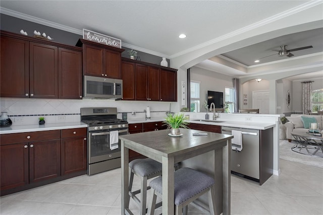 kitchen with stainless steel appliances, a peninsula, a sink, arched walkways, and open floor plan