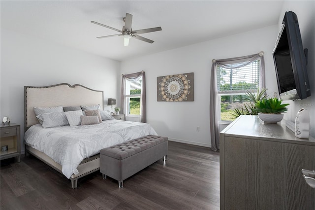 bedroom featuring baseboards, a ceiling fan, multiple windows, and dark wood-style floors