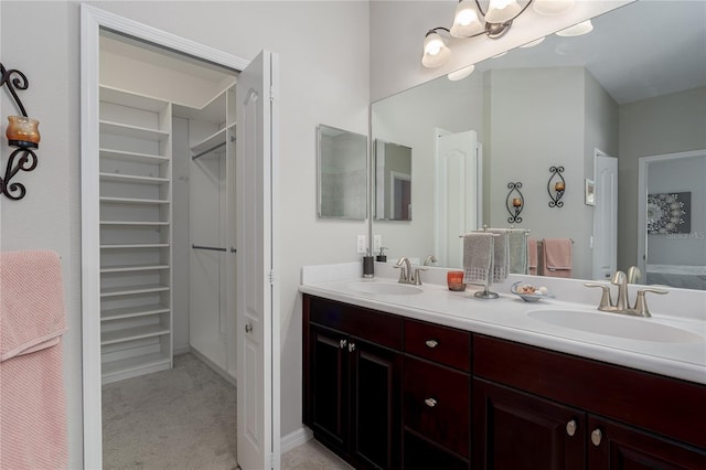 full bathroom with a walk in closet, double vanity, and a sink
