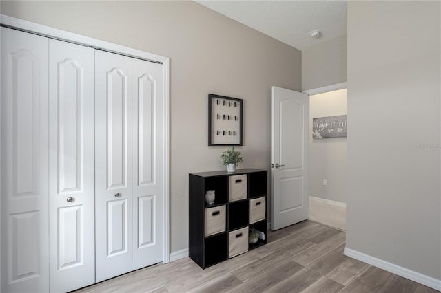 bedroom featuring a closet, light wood finished floors, and baseboards