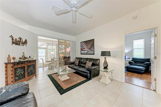 living room with light tile patterned floors, a ceiling fan, visible vents, and baseboards
