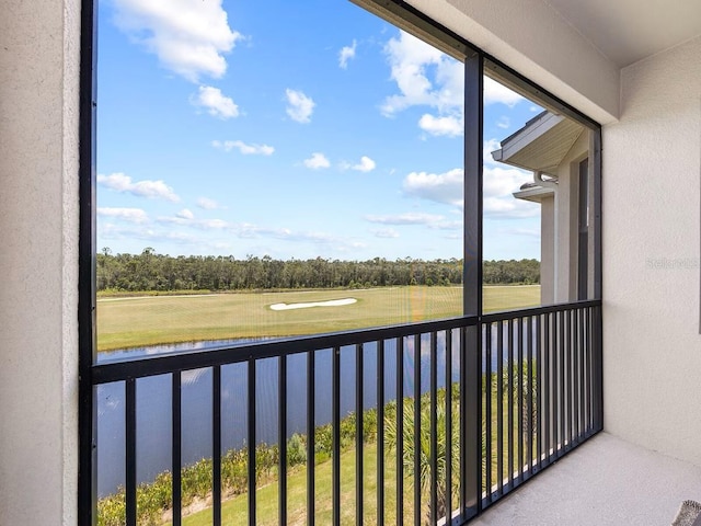 balcony with a water view, view of scattered trees, and golf course view